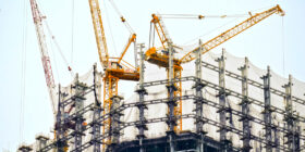 an upwards shot of two cranes on a building construction site