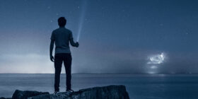 a man standing on a rock at the beach at night