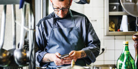 a chef texting on his phone in a kitchen