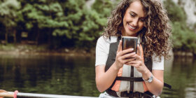 Woman looks at her phone while she is Kayaking on a lake